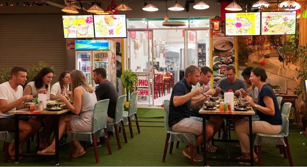 2. International travelers gather on the front patio enjoying steaming bowls of stone bowl pho at Anh Dat Restaurant